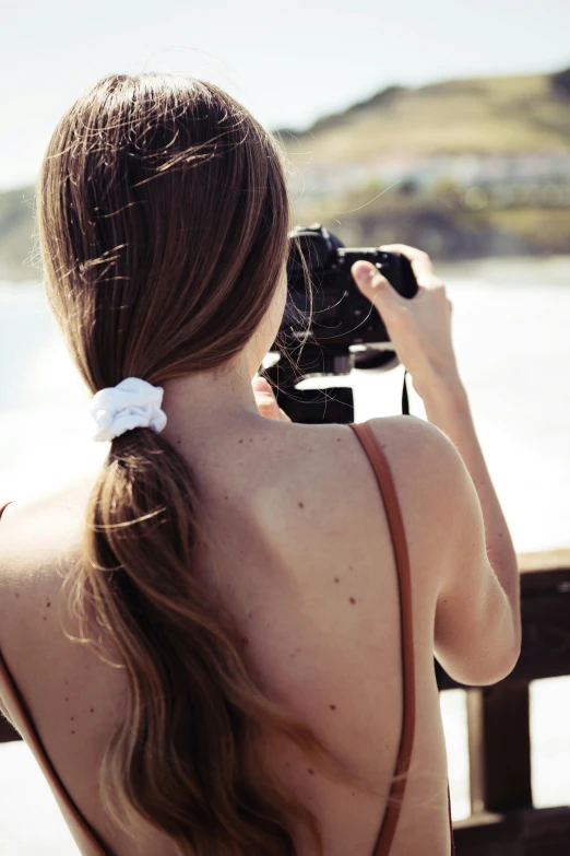 the girl has long hair and is holding her camera