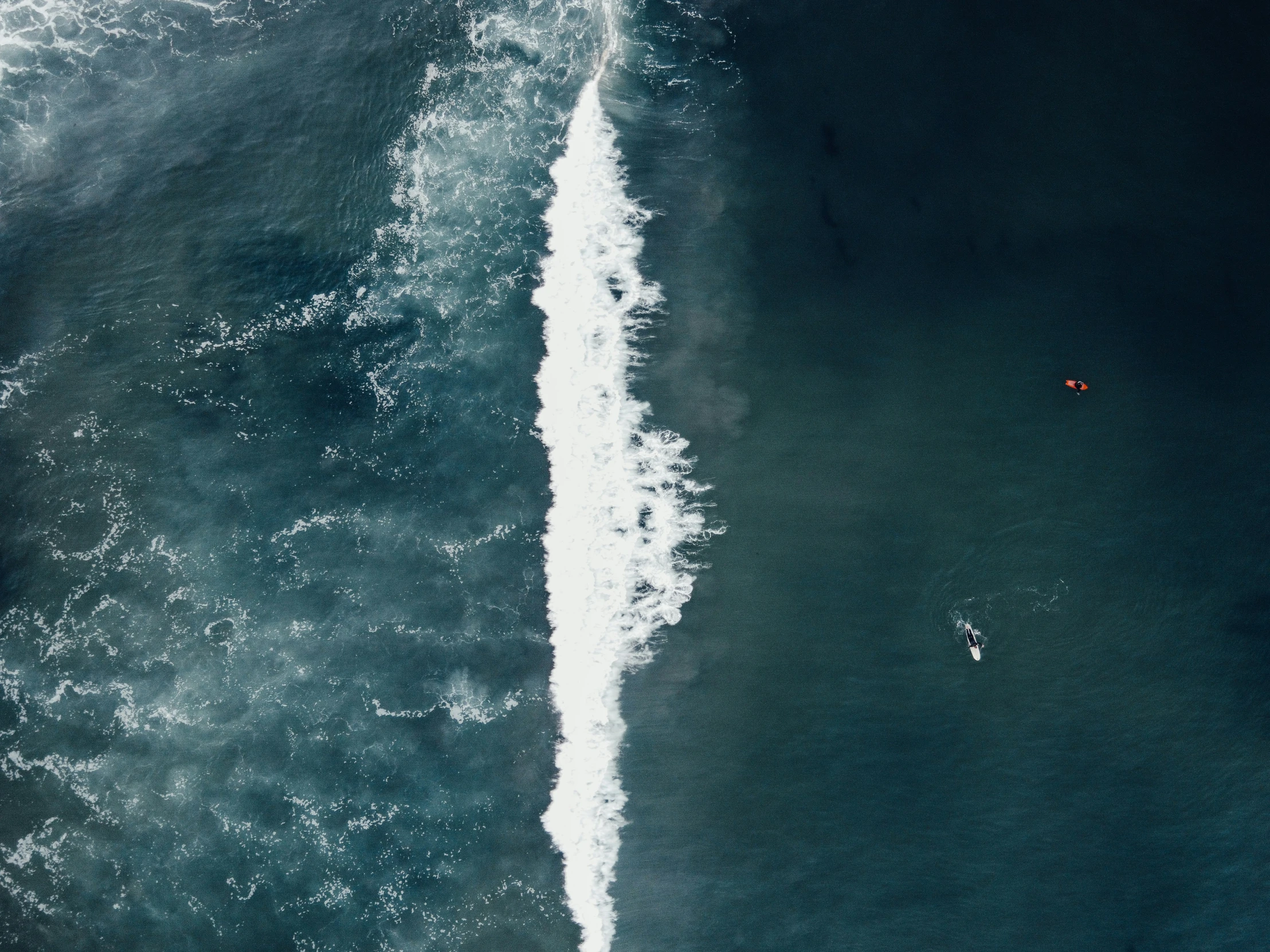 two people in small boats in the ocean with waves