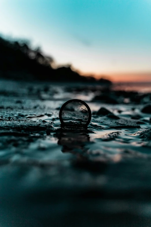 a single glass bottle in the water at sunset