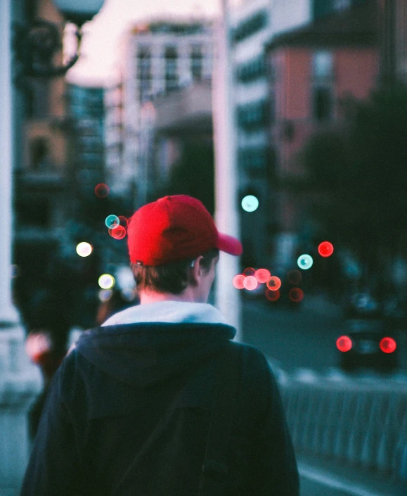 person with a red hat walking on a city street