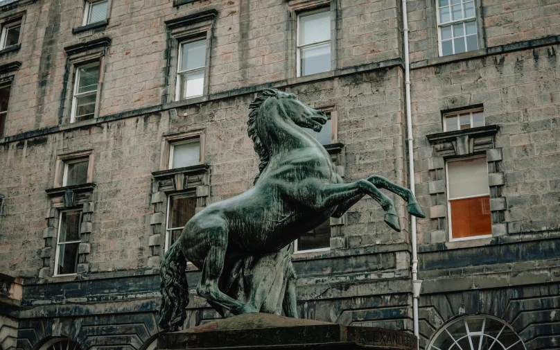 the statue of a horse is next to the building