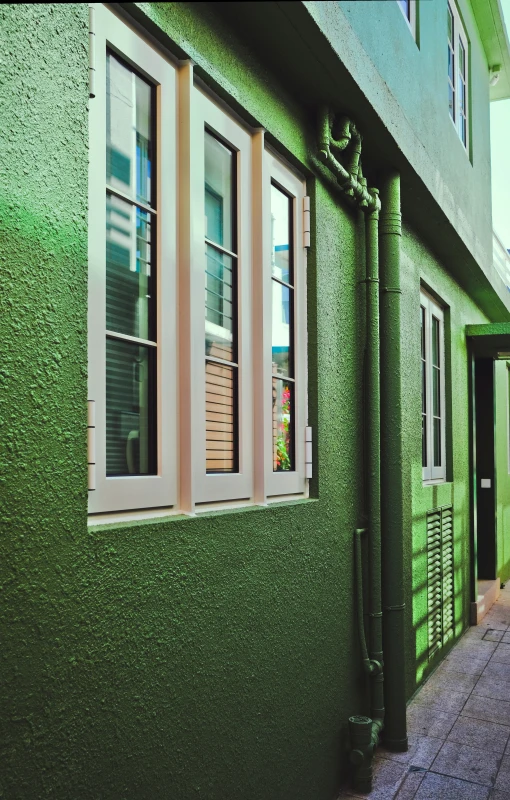 a green wall with many windows is painted green