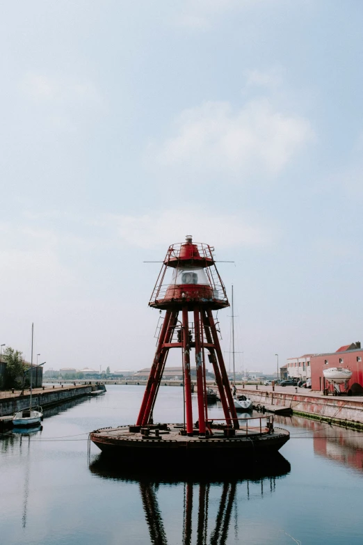 a boat sits on a river next to a red lighthouse