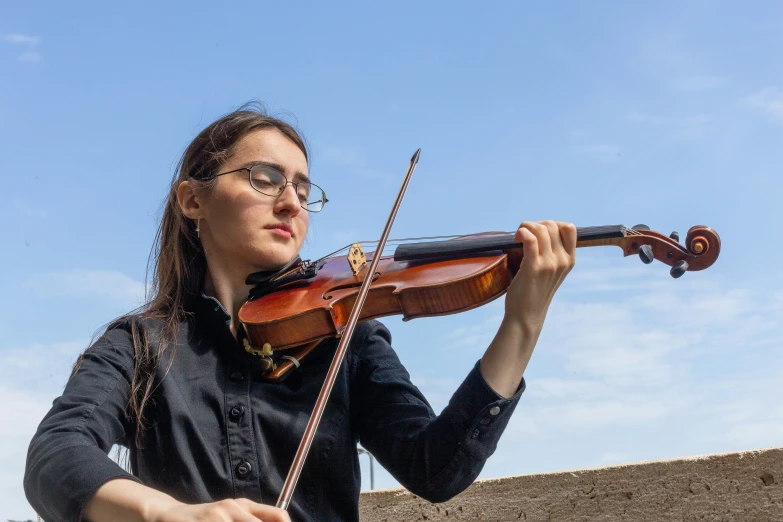 the young woman is playing the violin outside