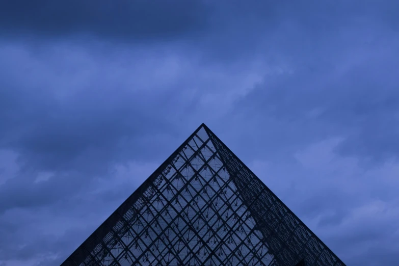 a very tall pyramid in the dark with cloudy sky