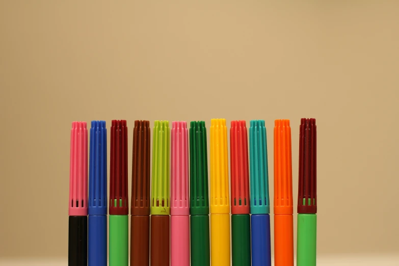 seven pens are lined up and one is orange