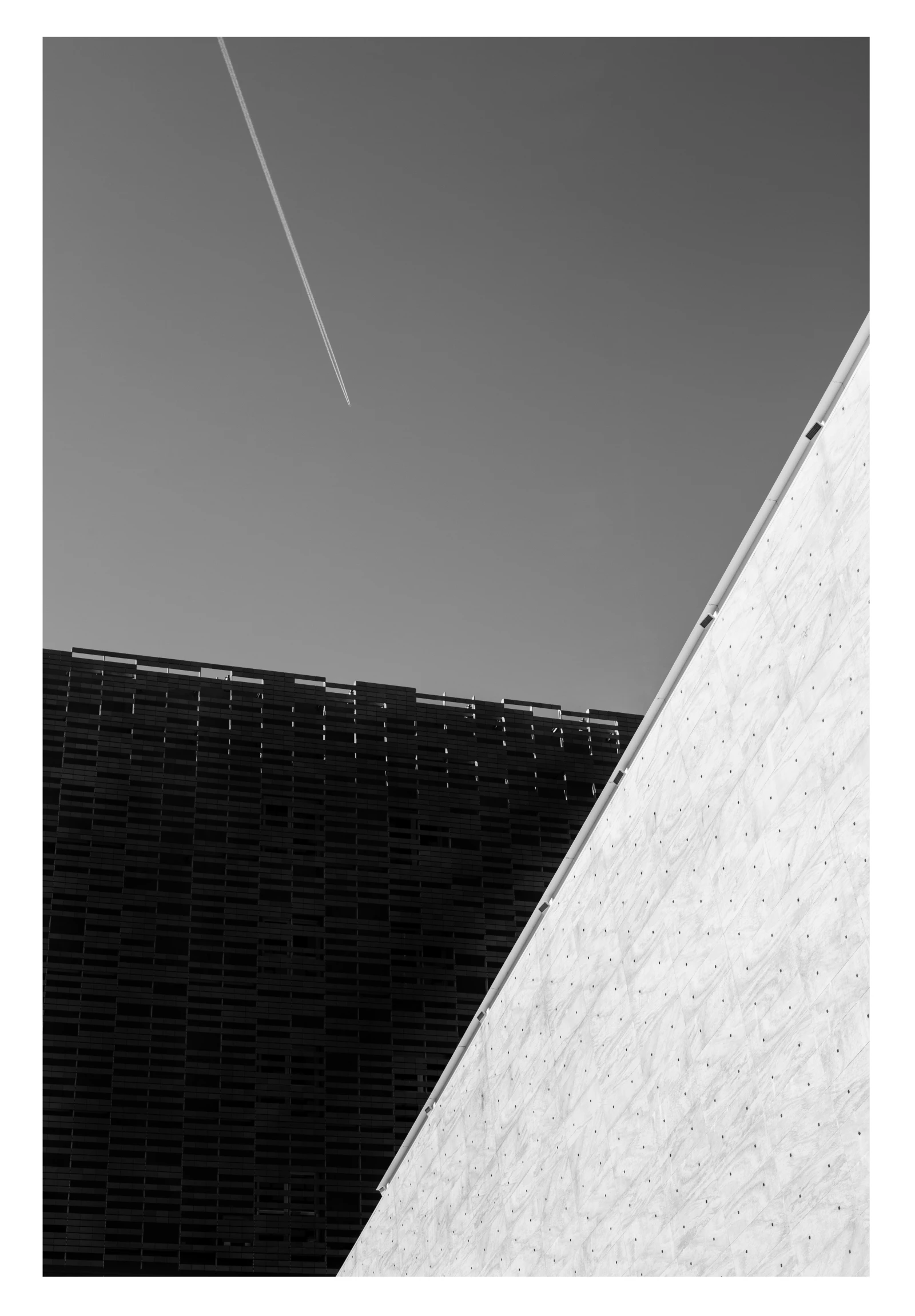a black and white po of a plane flying over the top of the building