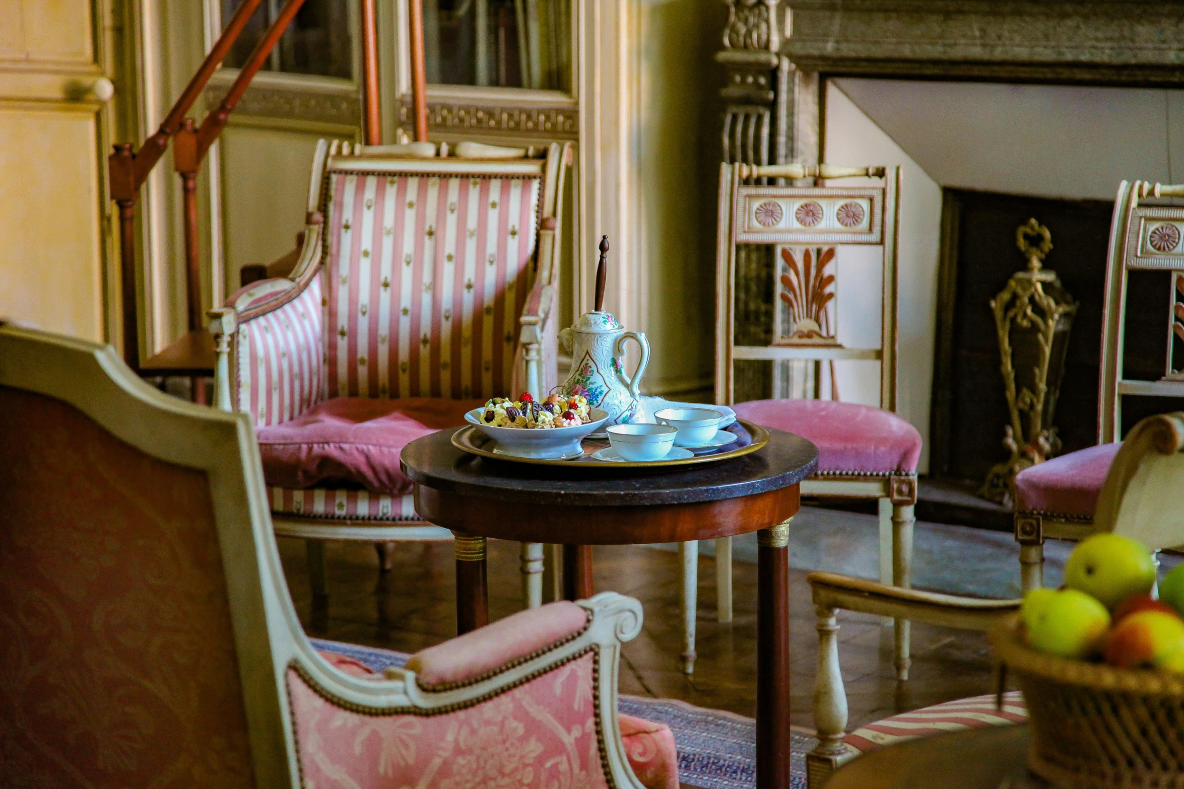 a formal dining room has pink upholstered chairs and chairs with matching foot rests