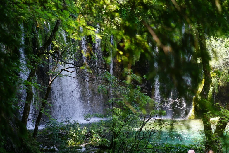 a view of people walking through the park near a waterfall