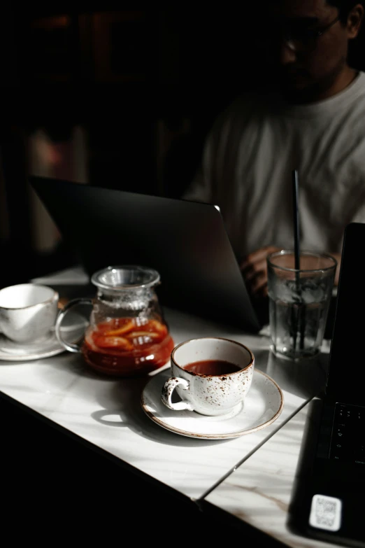 a laptop computer next to some coffee cups on a table