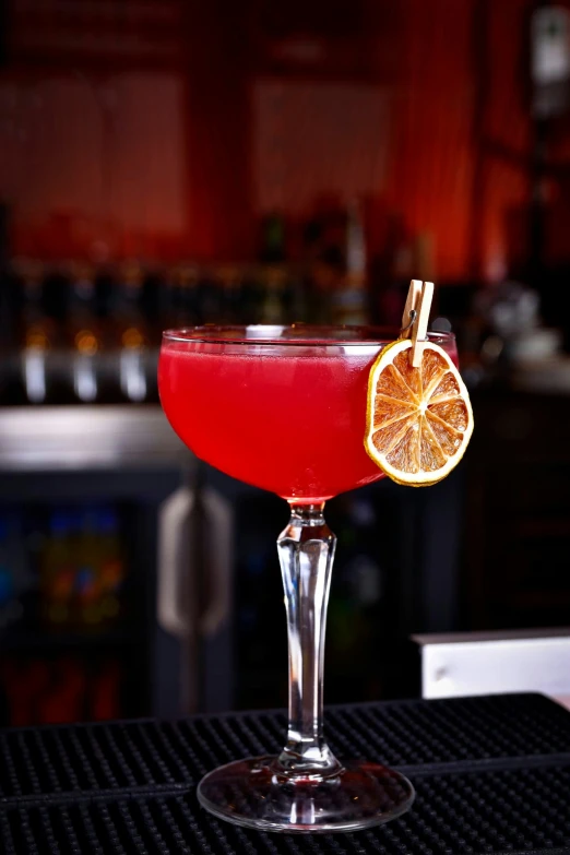 a close up view of the red cocktail that's garnished with a single lemon