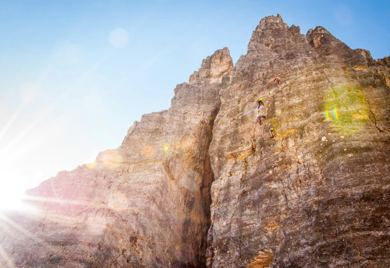 a very tall mountain with a sun shining behind it