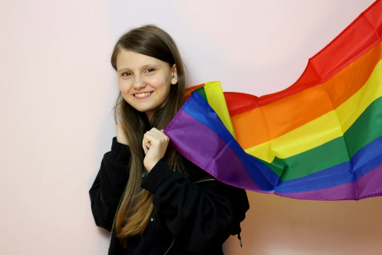 a young woman holding up her rainbow striped kite