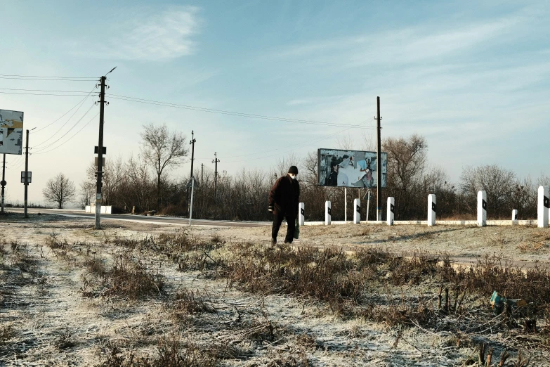 a man walks towards the road sign with a sky background