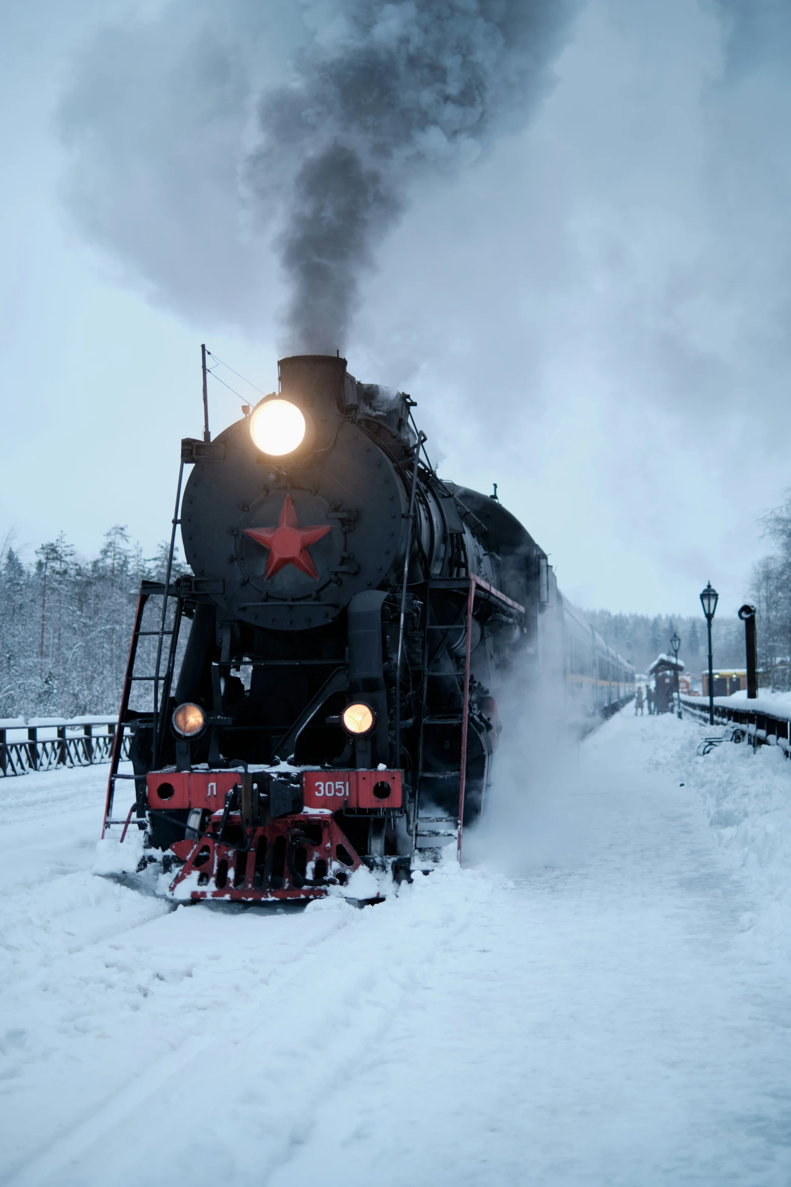 an old black steam locomotive moving through the snow