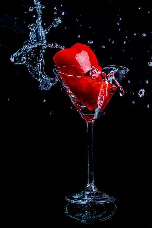 the red apple is splashing into a cocktail glass