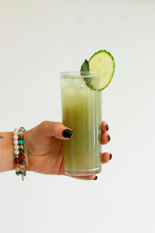 a person holds a glass of cucumber juice