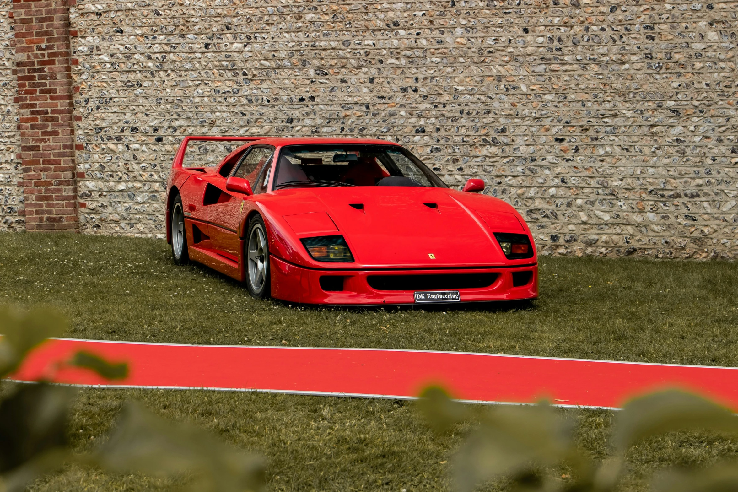 a red sports car parked in front of a brick wall