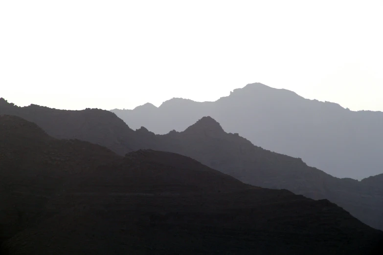 a lone airplane flies over a mountain range