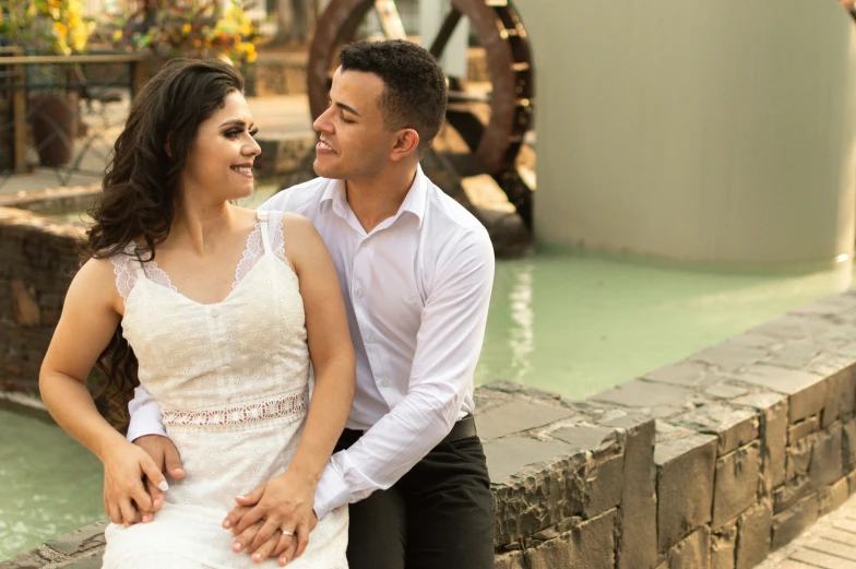 the couple is smiling for a po while sitting next to a river