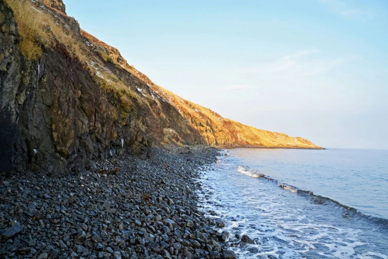 the shore line next to a rocky, steep cliff