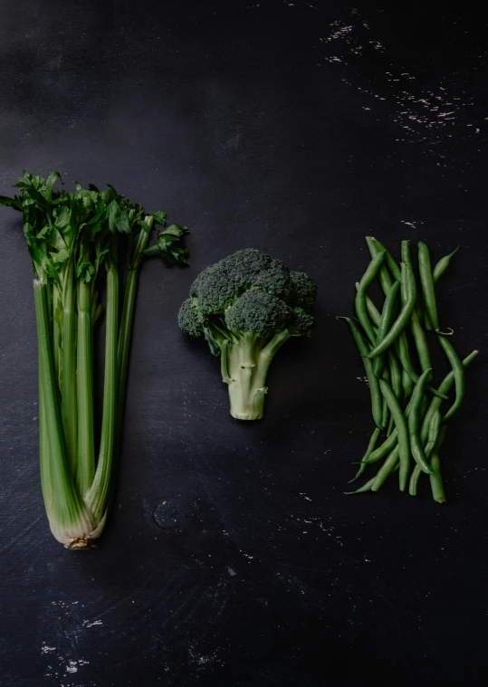 two pieces of broccoli, a head of broccoli and a few green beans