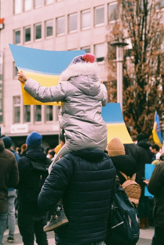 a person wearing a hooded coat holding a blue and yellow flag