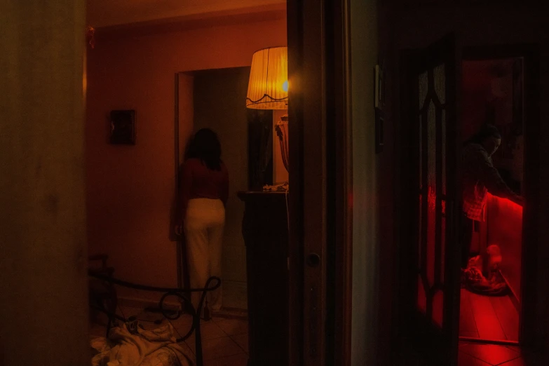 a woman in a white dress with a light on looking into her room