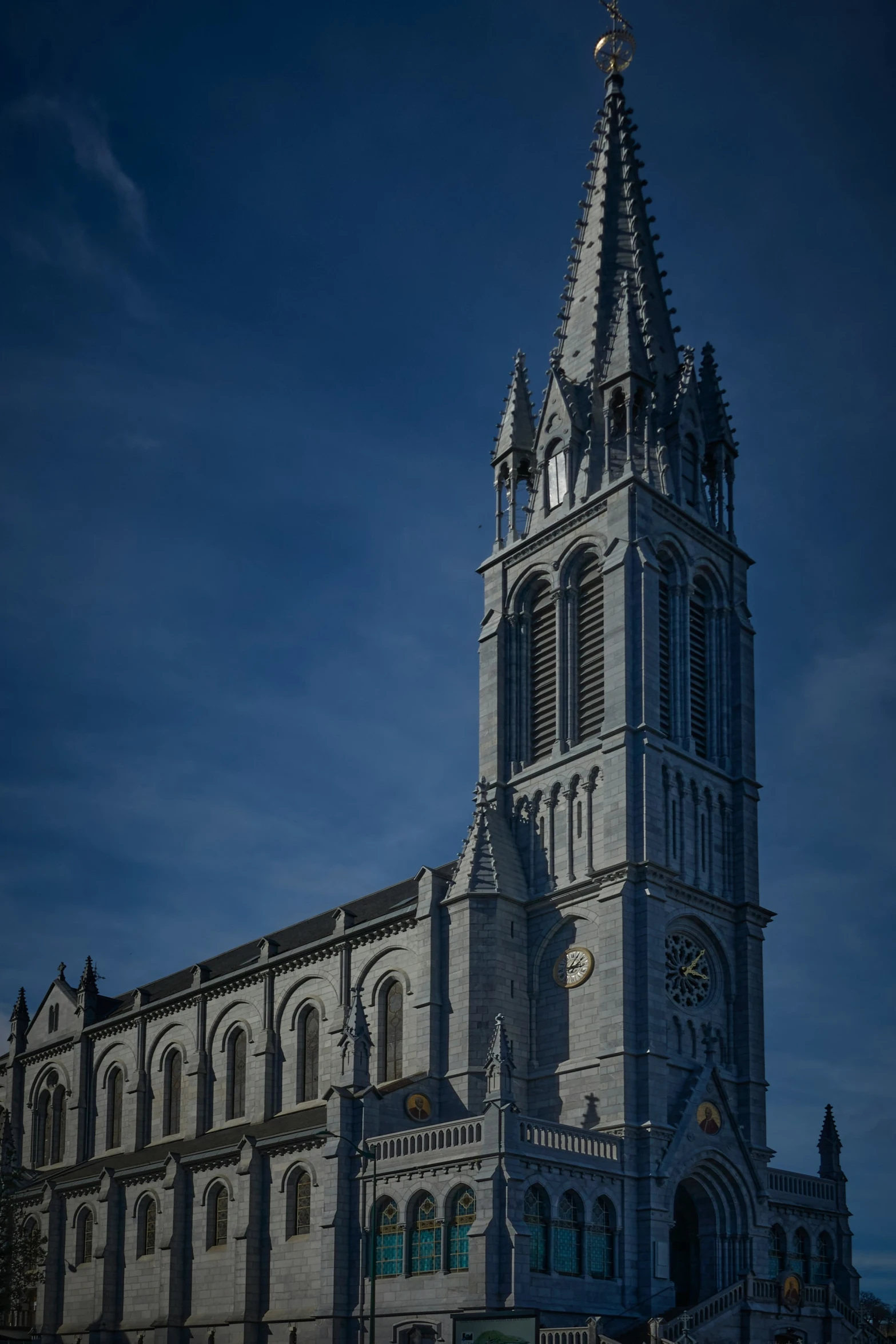 a tall cathedral with two clocks in front of a cloudy sky