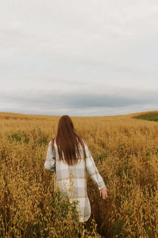 a woman in a field of wheat looking for soing