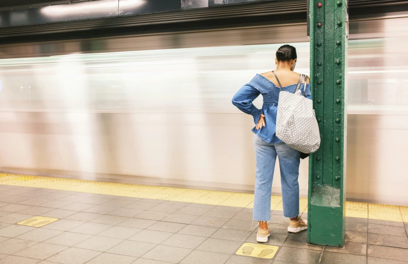 a woman standing on a platform waiting for a subway train