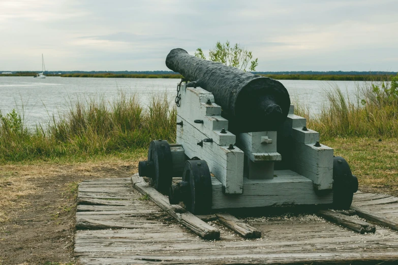 a wooden cart with an old military cannon on the ground