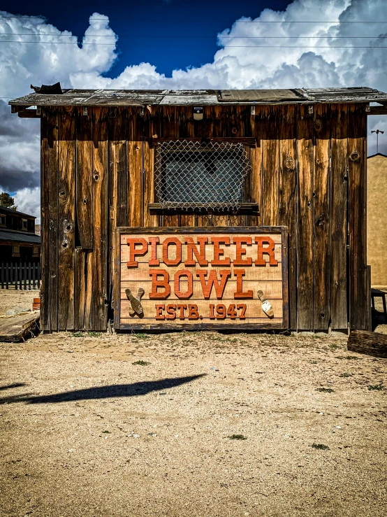 a wooden building in a barren area near some buildings