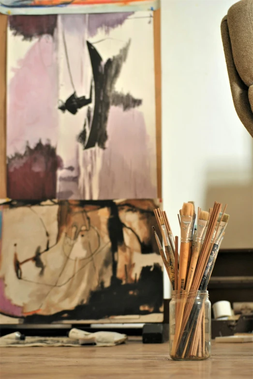 the pencils are lined up in front of a paintbrush holder on a wooden table