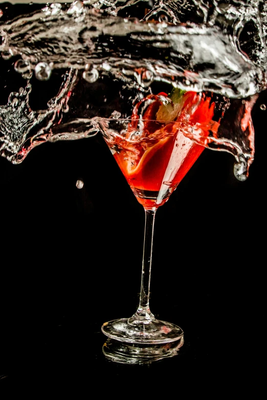red cocktail being poured with water in a wine glass