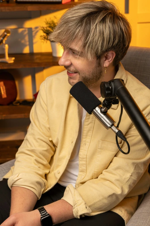 a young man with long hair, with a microphone on his neck