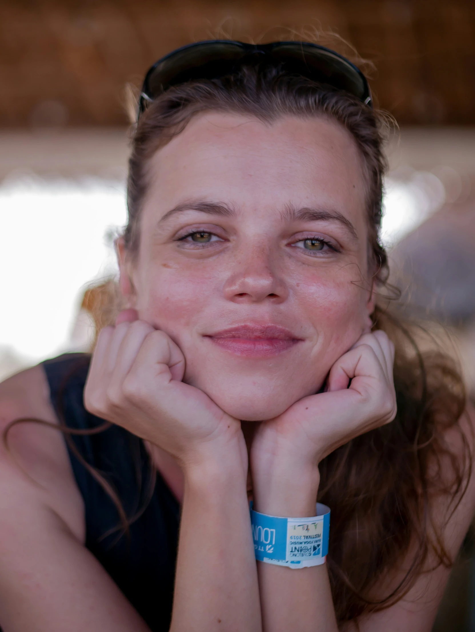 a woman wearing a wrist celet and sunglasses on her neck