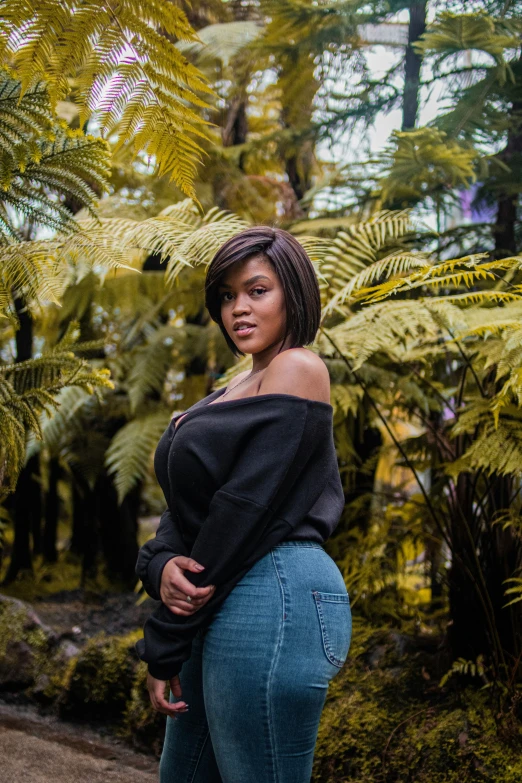 a woman in jeans is posing with a tree in the background