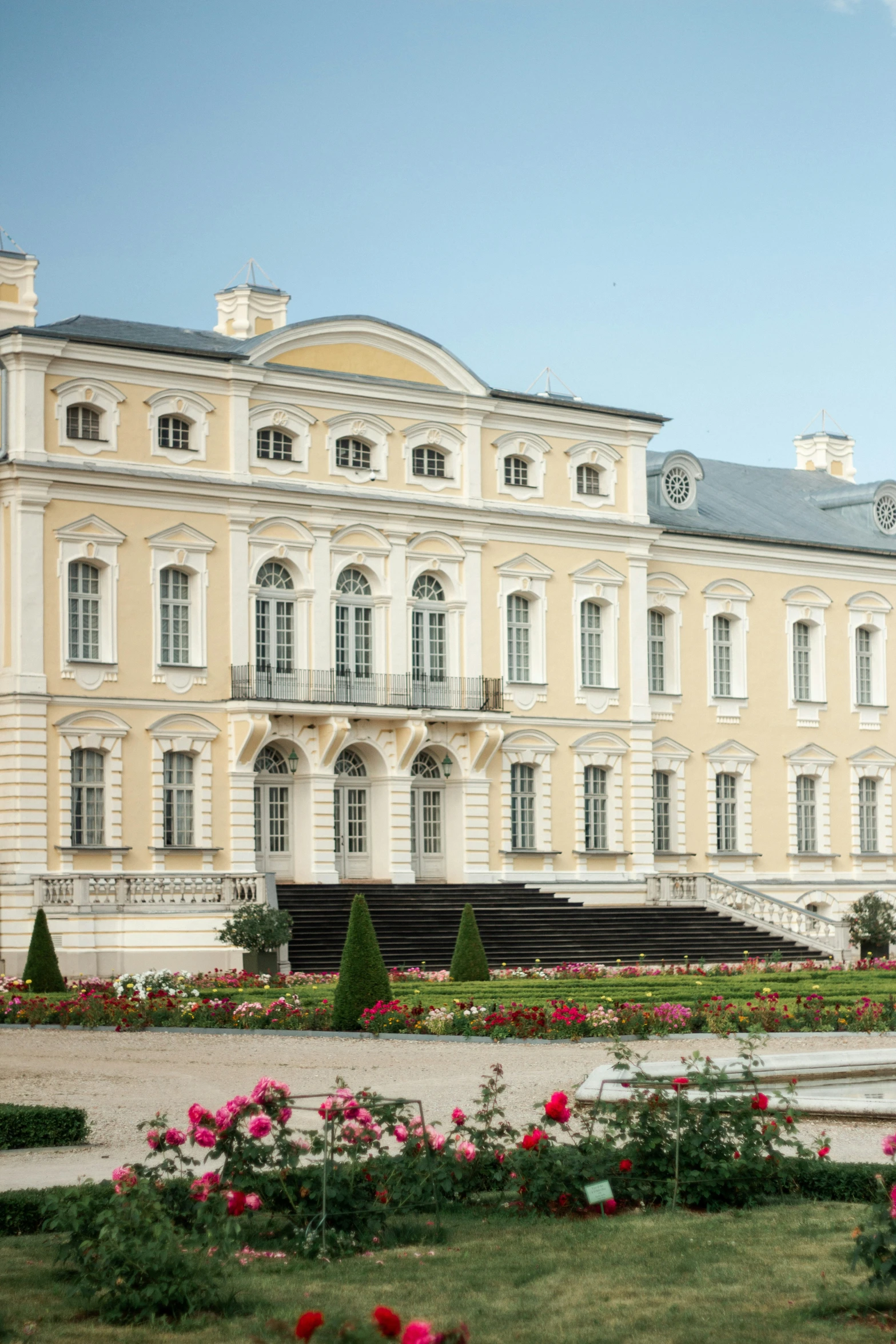 a large building is shown with roses and bushes around it