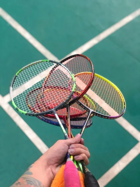 a person holding three tennis racquets in each hand