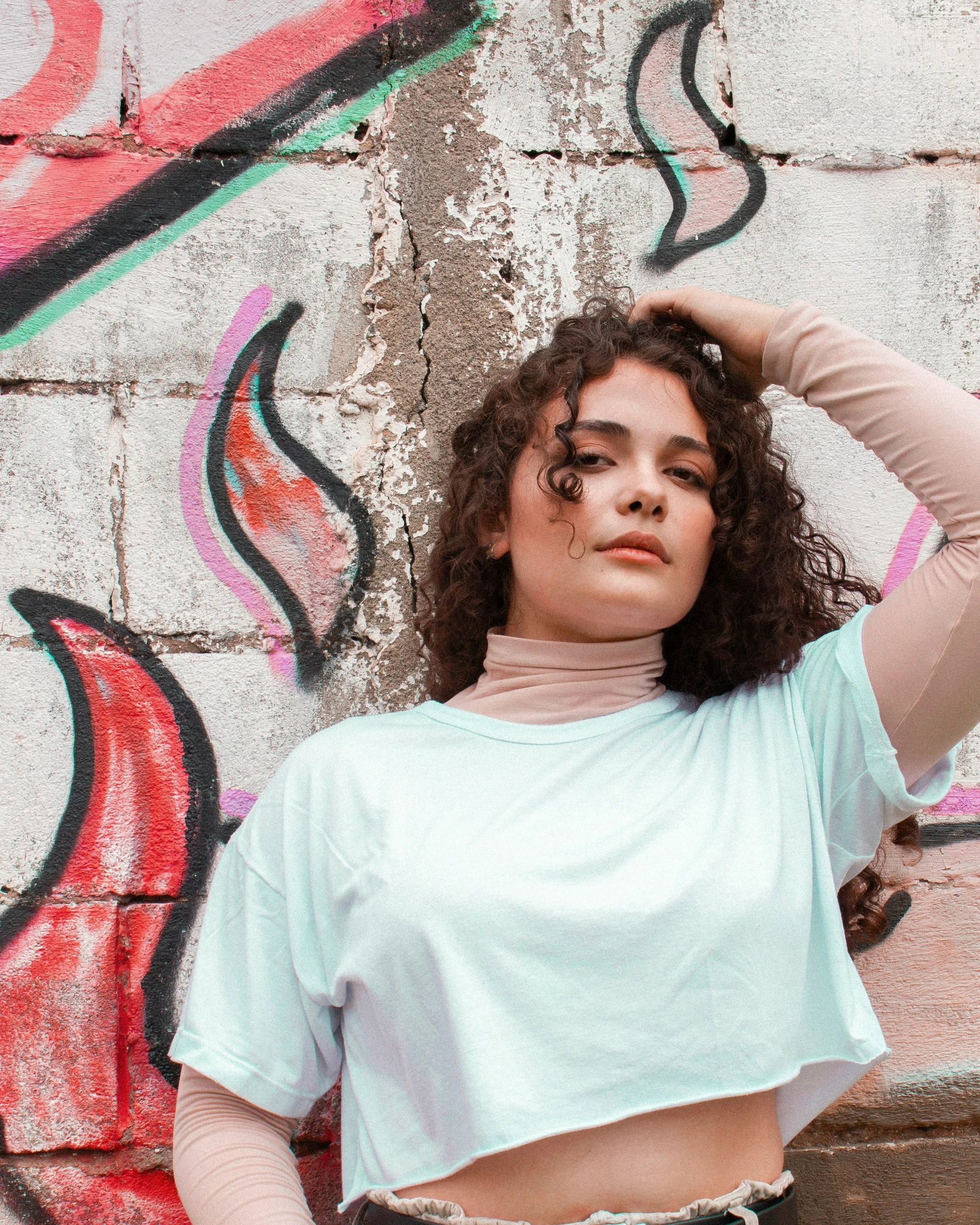 a woman posing in front of a brick wall