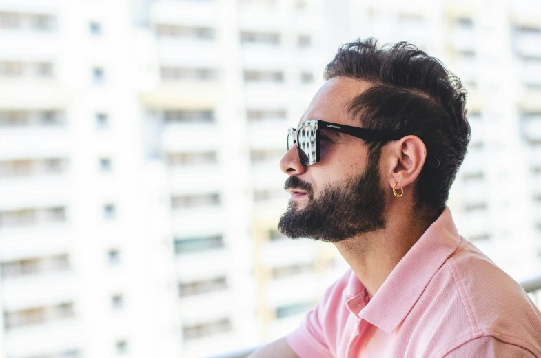 the bearded man in glasses is standing next to an apartment building