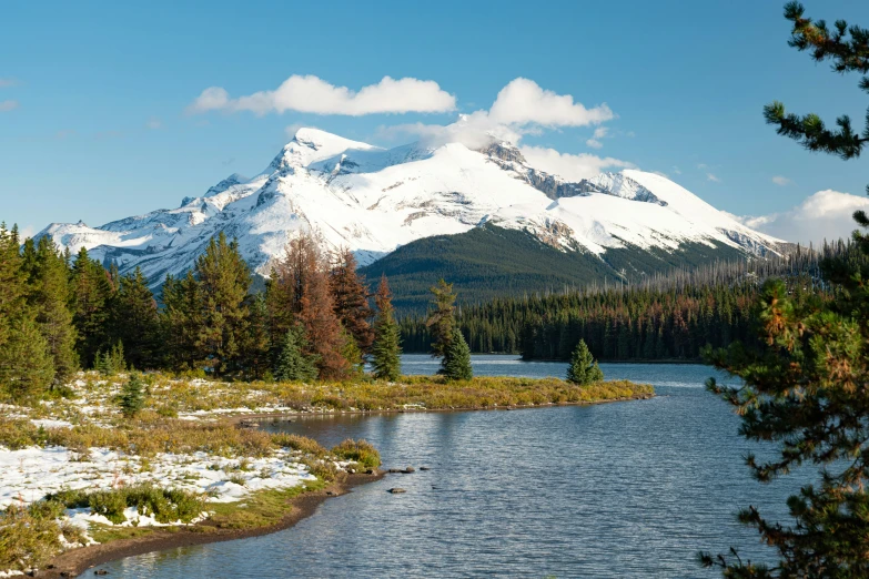 a mountain view of a river with snow capped peaks