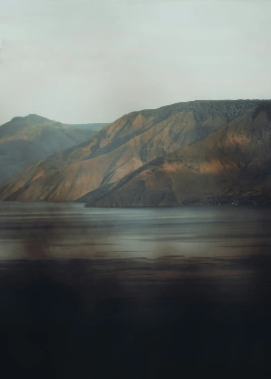 a mountain covered in trees and water next to mountains