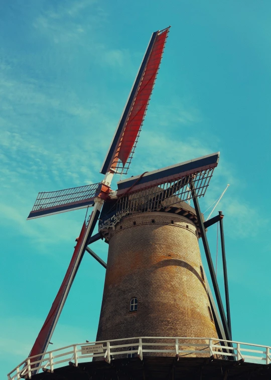 a windmill with a red tail and a blue sky