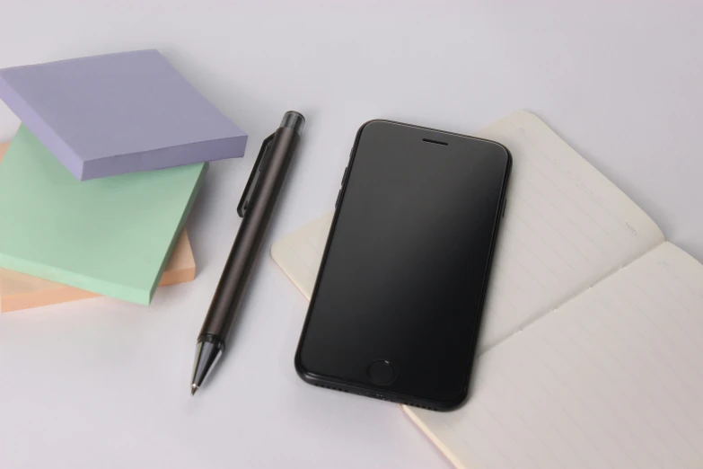 an apple iphone next to a pen on top of papers