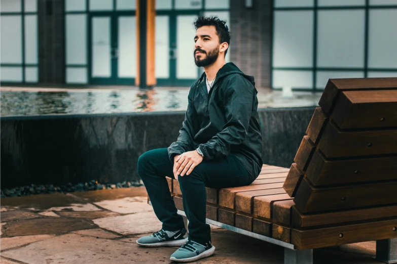 a man sitting on a bench in the rain outside