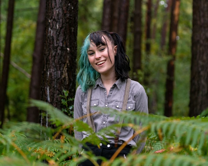 a young woman standing among some tall plants in the woods