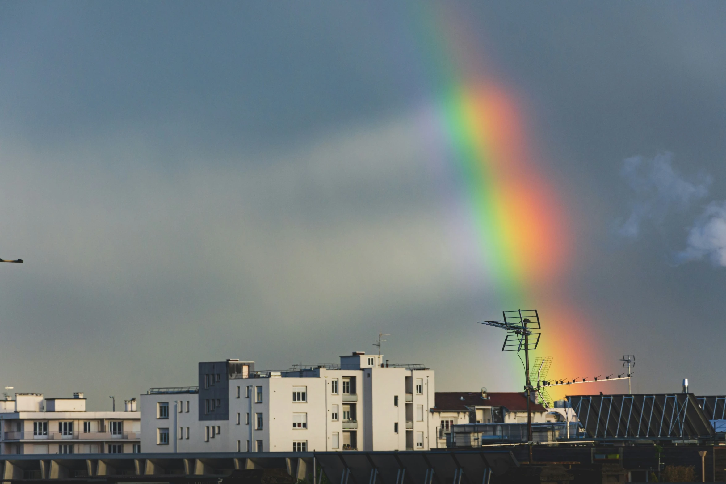 a rainbow with dark gray skies is lit against the backdrop