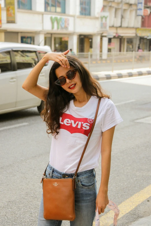 a girl in white shirt and jeans holding a brown purse